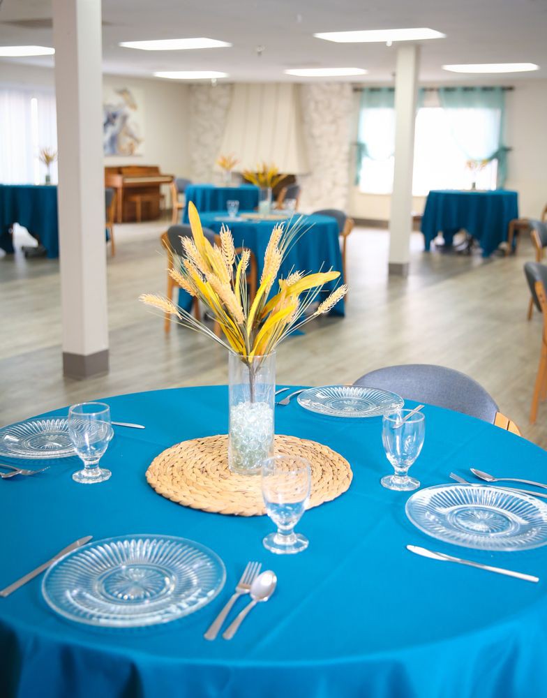 An elegantly set dining table with a blue tablecloth and a decorative centerpiece in a bright, spacious room.
