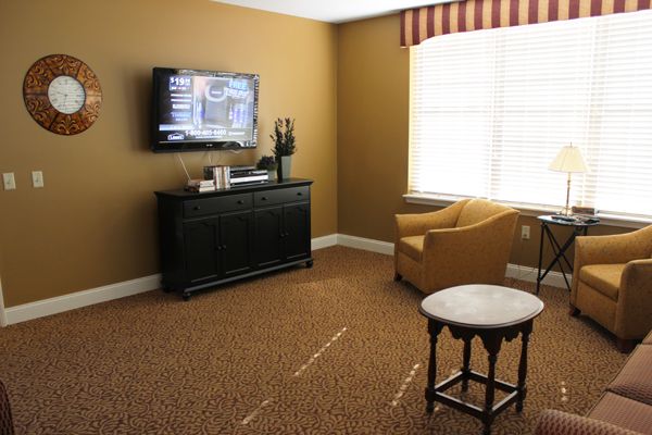 A cozy living room with a wall-mounted television, an armchair, and a small table.