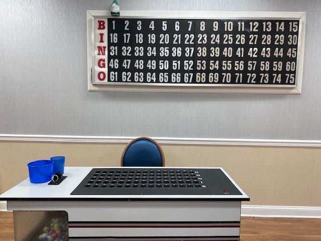 A bingo hall setup with a number board and table.