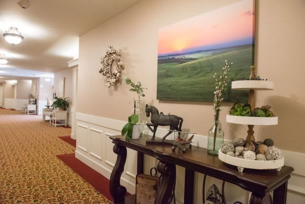 A well-decorated hallway with a side table featuring a horse statue, plants, and artwork on the wall.