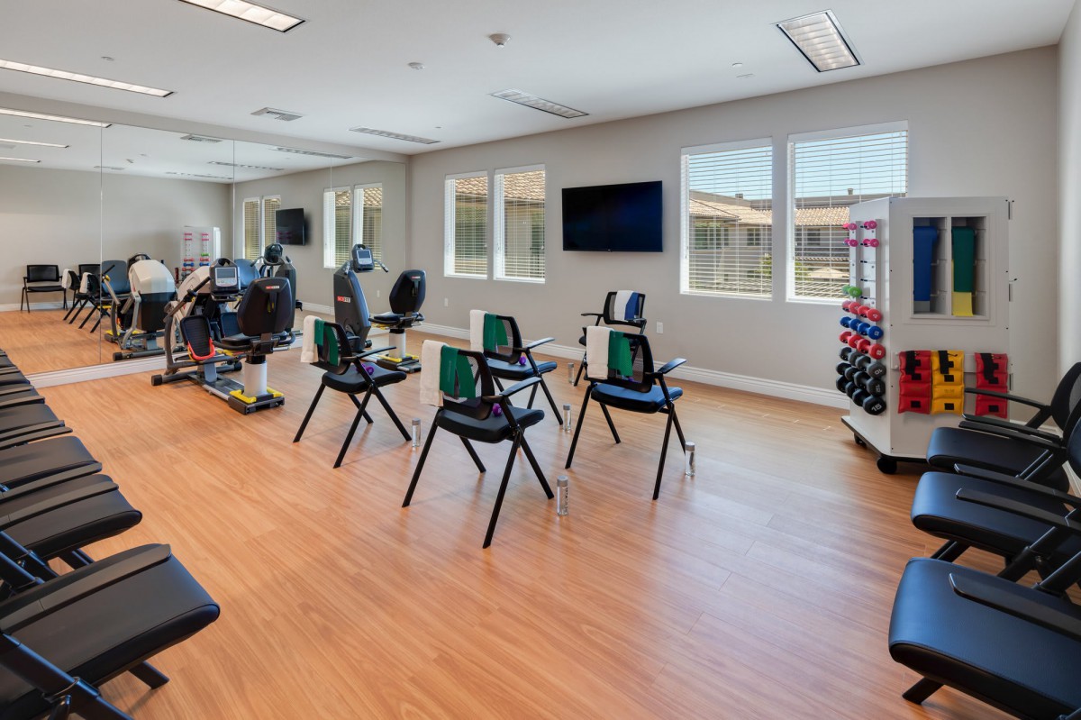 A spacious gym studio equipped with exercise chairs and weights for fitness activities.