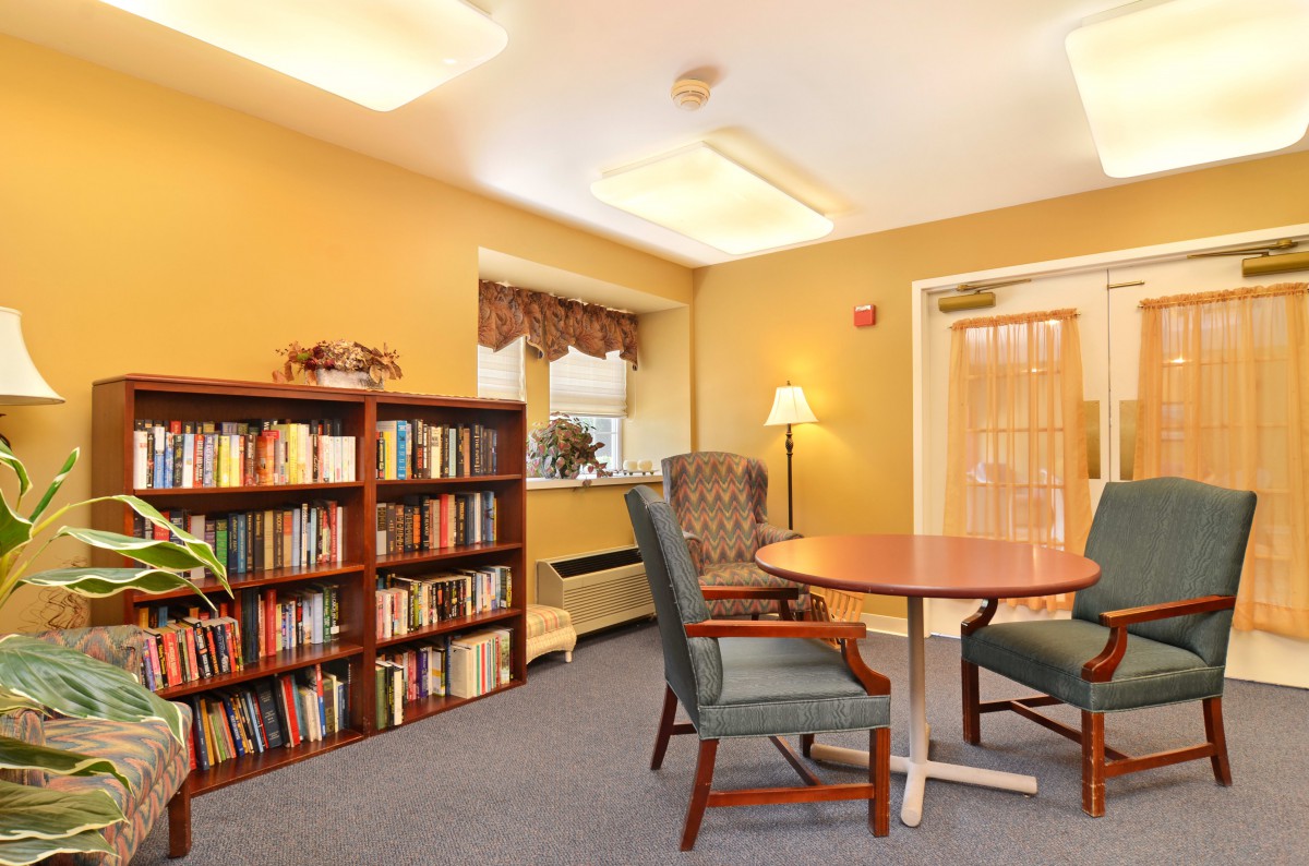A cozy reading room with bookshelves, a table, and chairs.