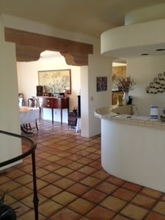 A cozy interior with a tiled floor, featuring a dining area through an archway and stylish decor.