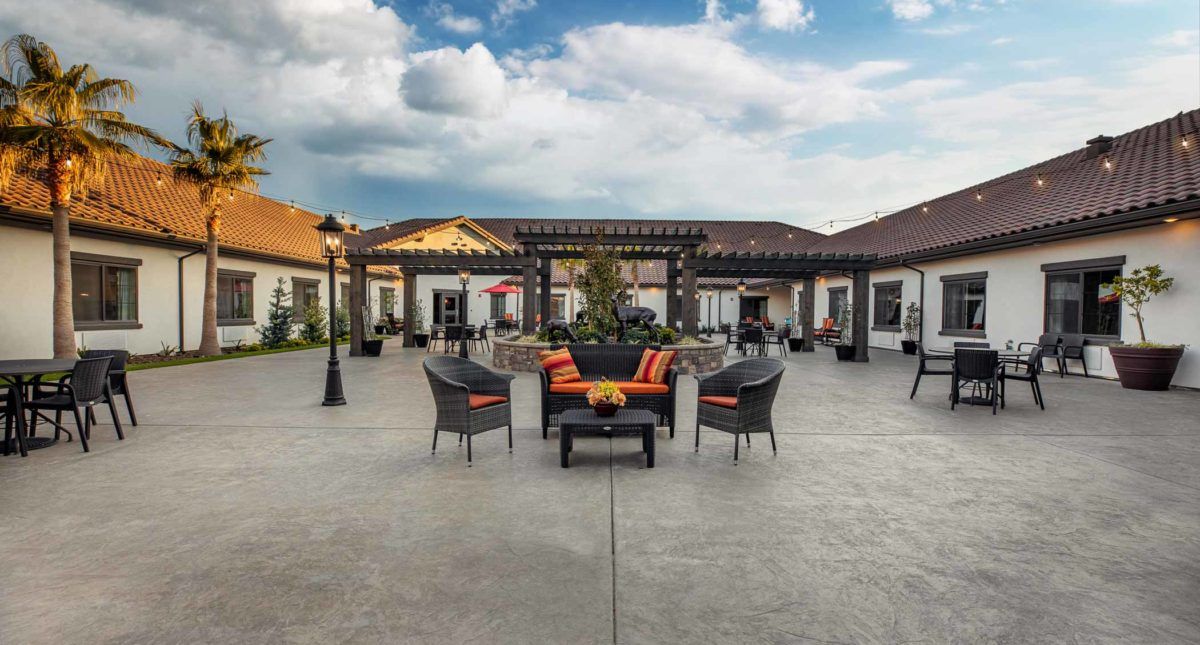 A spacious outdoor patio with comfortable seating and a pergola under a partly cloudy sky.
