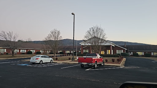 A peaceful evening view of a building surrounded by parked vehicles and distant mountains.