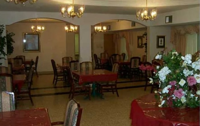 An empty dining area with chandeliers and elegantly arranged tables and chairs.