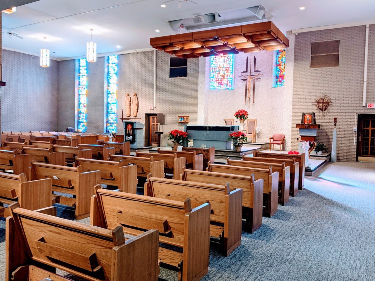 Interior of a church with wooden pews and a decorated altar.