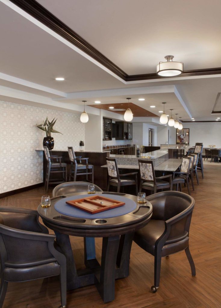 A modern lounge area featuring elegant seating, decorative lighting, and a game table.