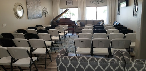 A cozy interior space set up with chairs for an event, featuring a piano in the corner.