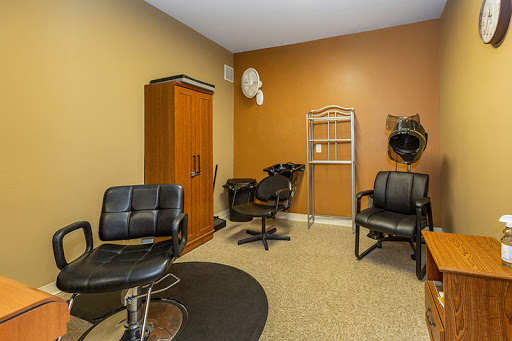 A cozy hair salon space featuring black chairs and warm wall colors.