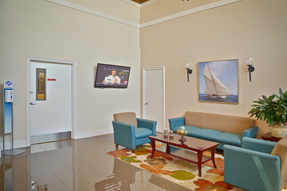 A modern waiting room with comfortable seating, featuring a television and nautical-themed artwork.