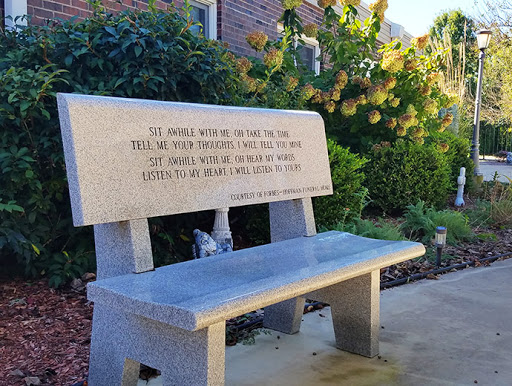 A beautifully crafted stone bench featuring an inscription, set in a serene outdoor environment.