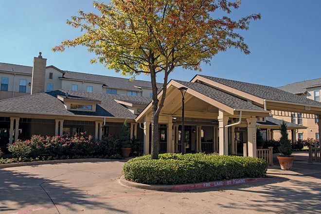 A building entrance with a tree and landscaped area in front.