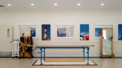 A well-lit workshop featuring a blue work table and decorative photographs of lighthouses on the walls.