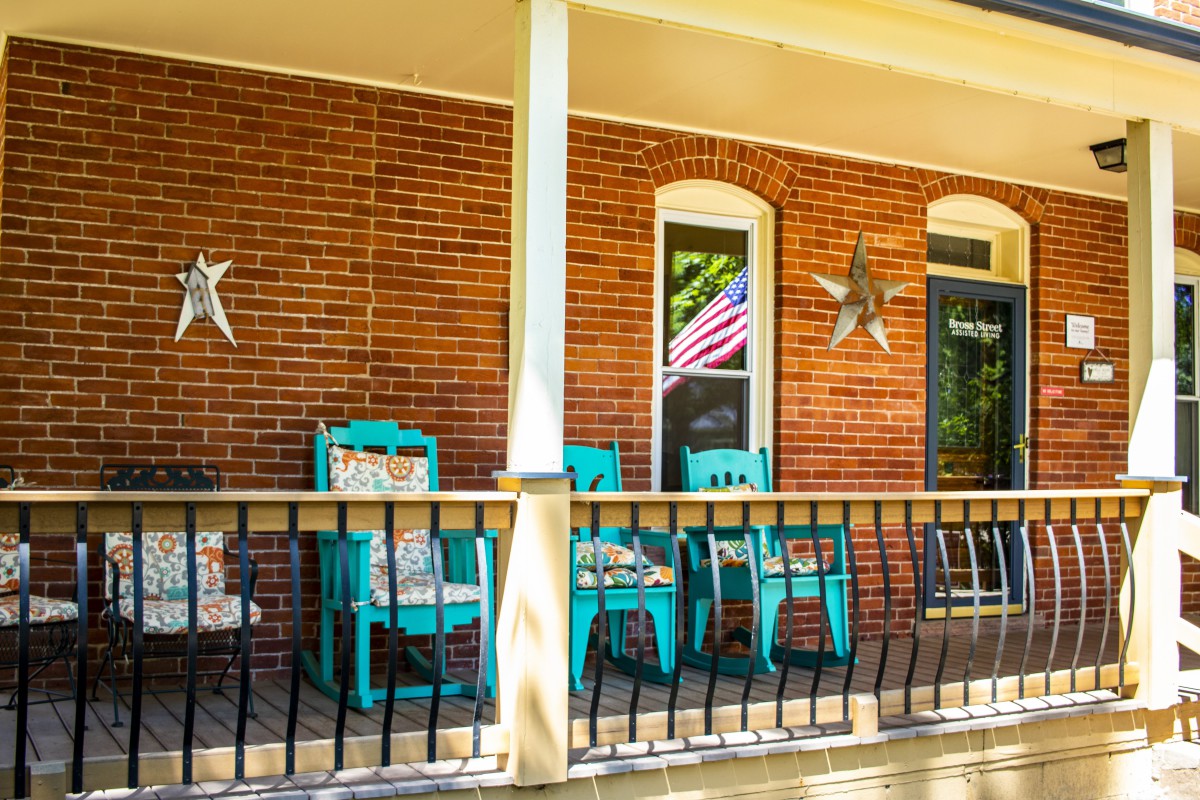 A charming front porch with turquoise chairs and decorative elements against a brick wall.