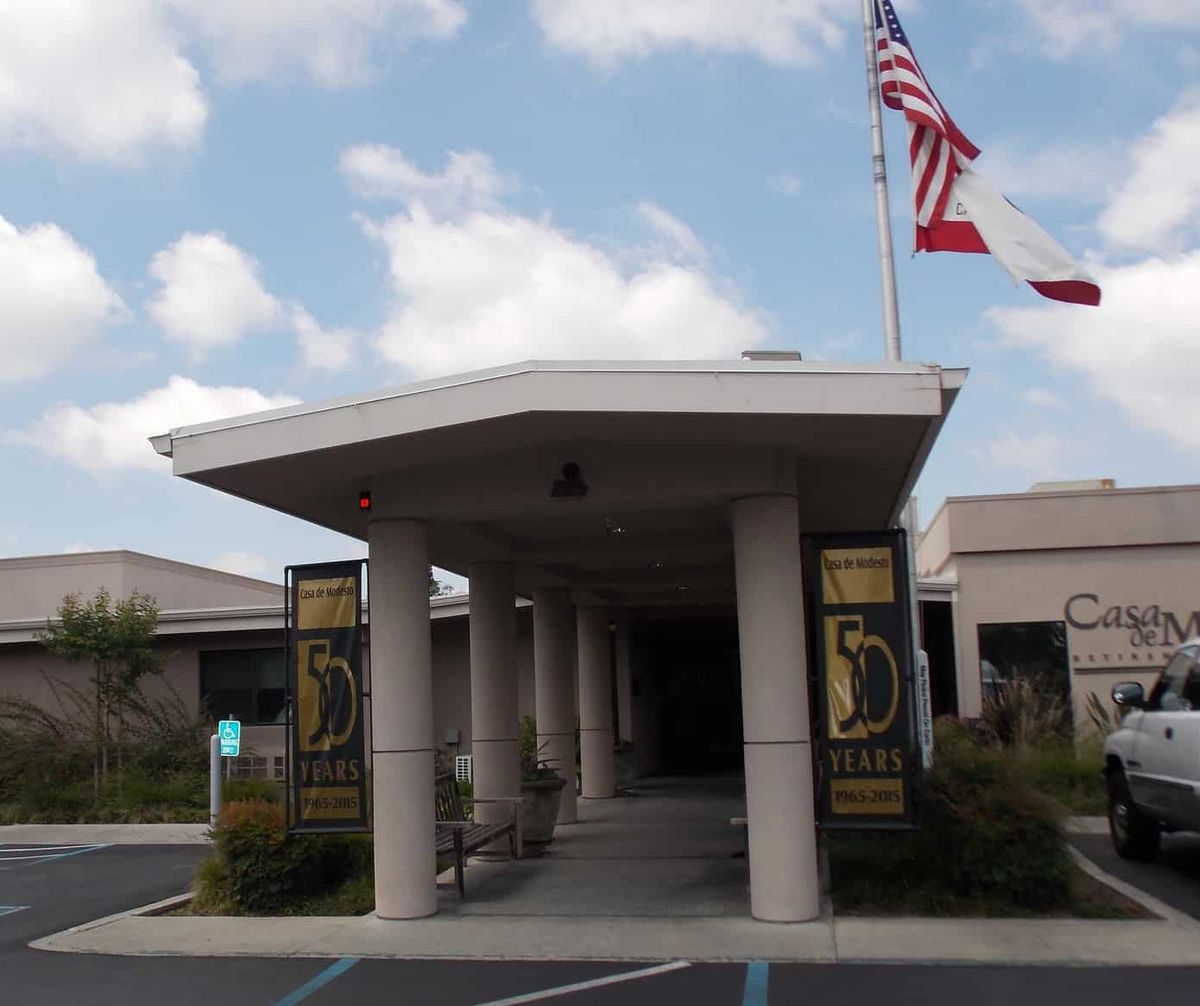 A building entrance with columns and flags flying on a clear day.