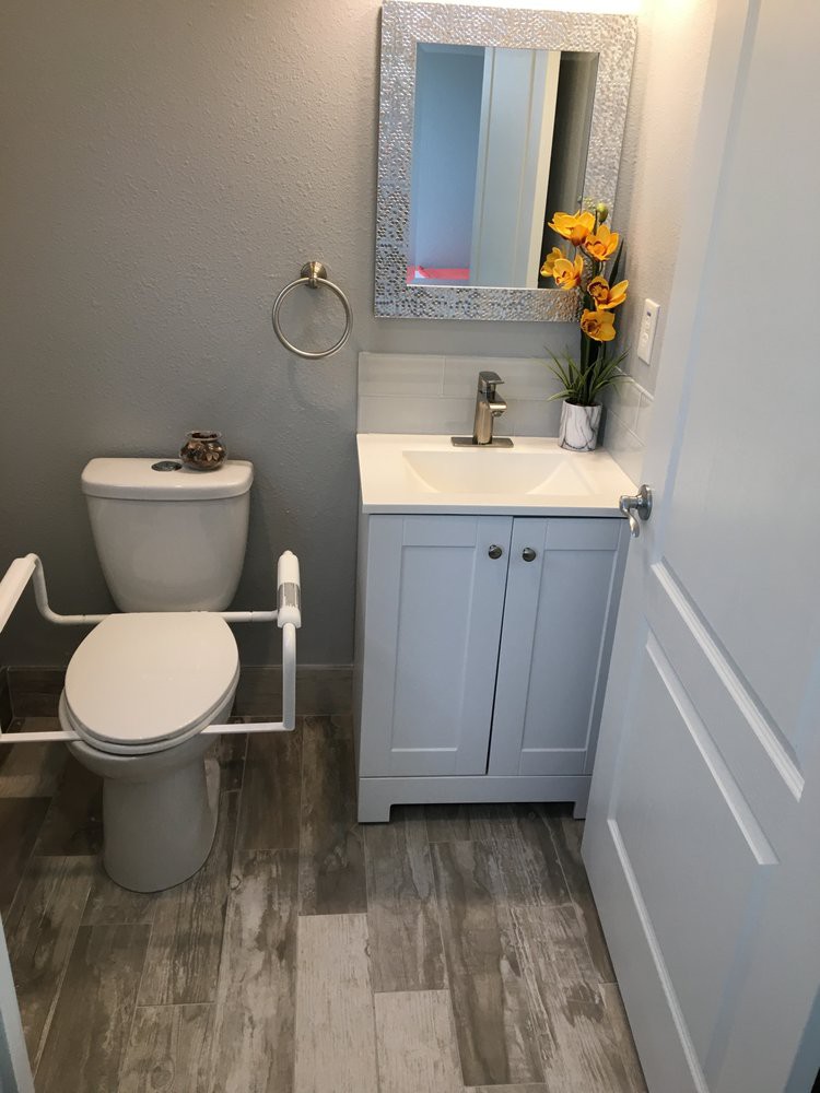 A small, modern bathroom with a toilet and sink, featuring decorative flowers and a mirror.