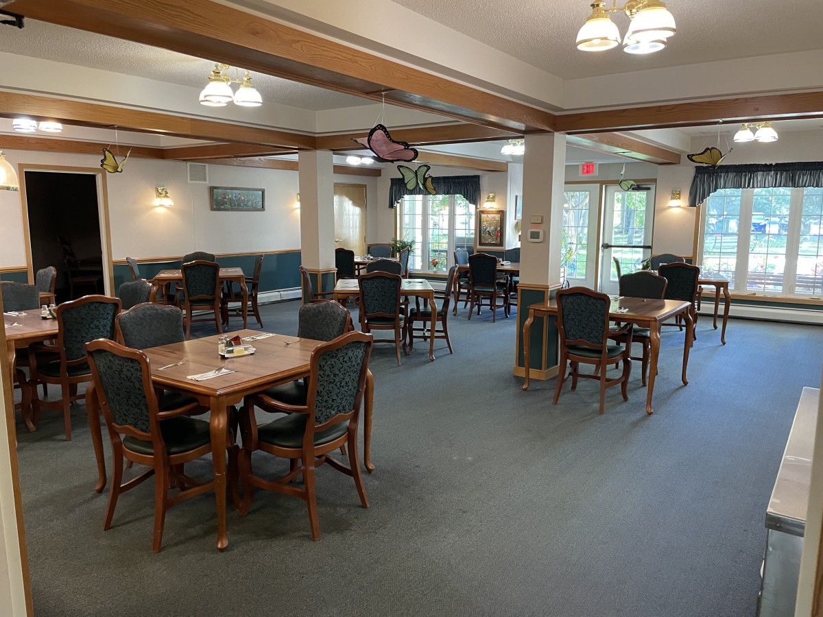 A spacious dining room with wooden furniture and carpeted flooring.
