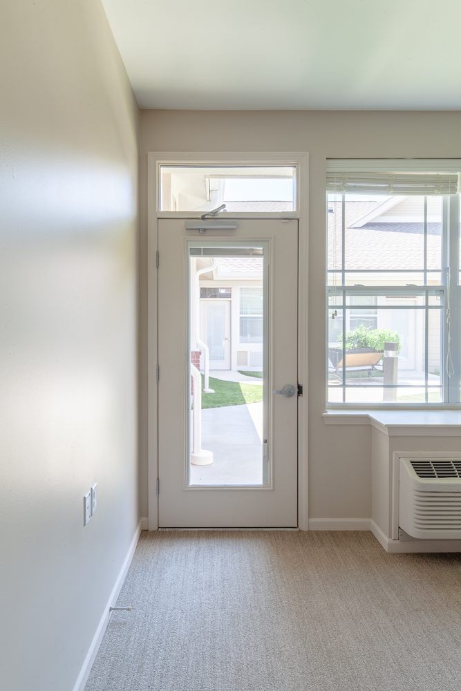 A bright interior with a glass door leading outside and a large window letting in sunlight.