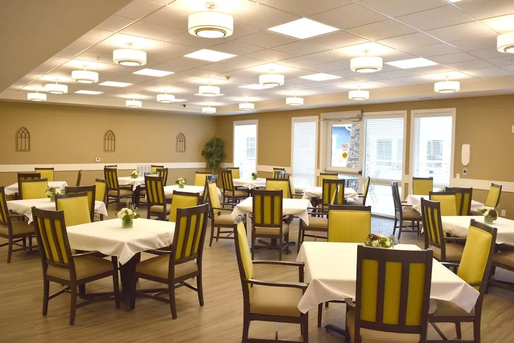 A spacious dining area with neatly arranged tables and chairs under modern lighting.