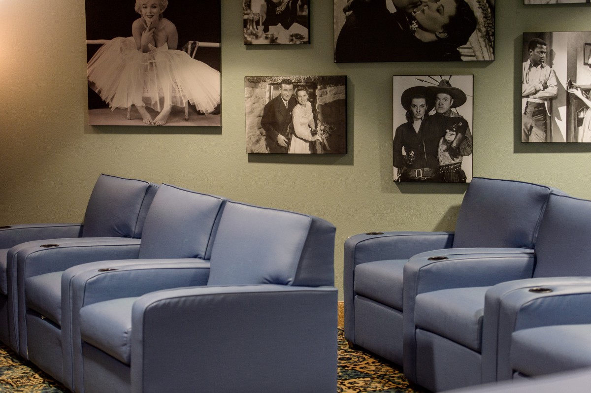 A cozy theater room with blue seating and classic posters on the wall.