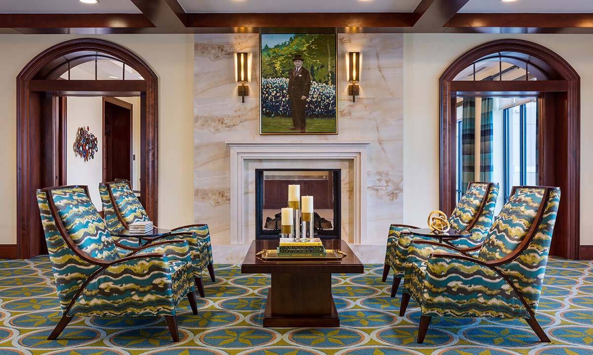 A luxurious living room with a central fireplace, surrounded by patterned chairs and elegant decor.