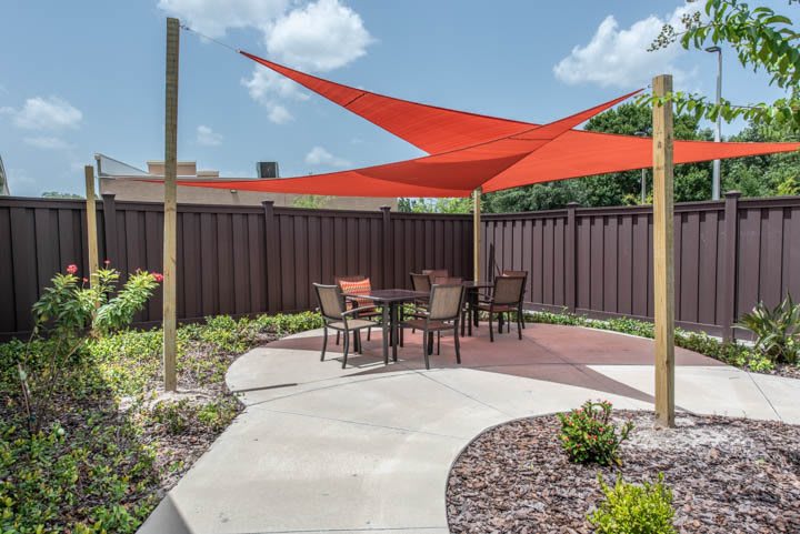 A patio area with a red shade sail and outdoor furniture.