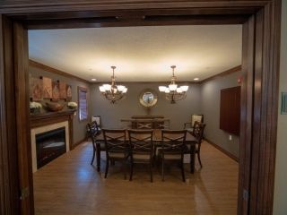 A cozy dining room with a large table, chairs, a chandelier, and a fireplace.