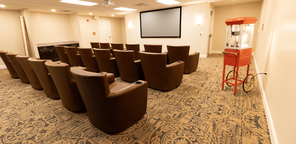 An intimate movie theater setup with several rows of comfortable chairs facing a large screen.
