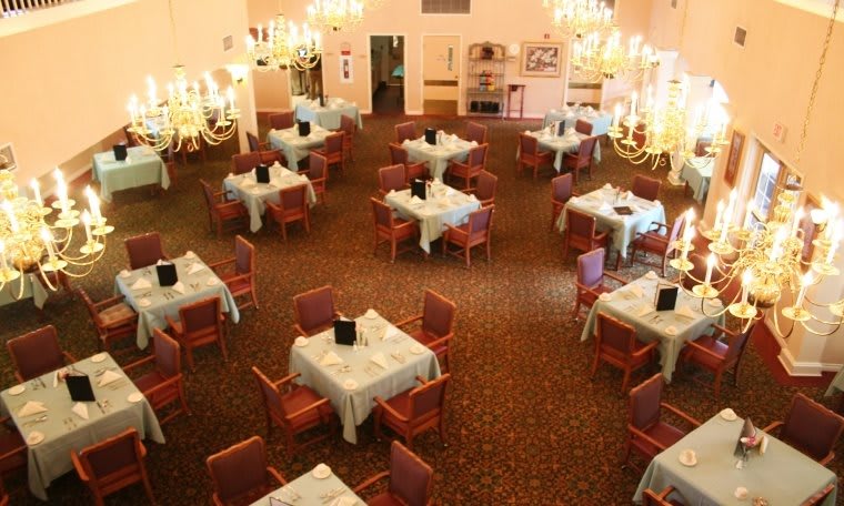 An elegant dining room with multiple tables and chandeliers.
