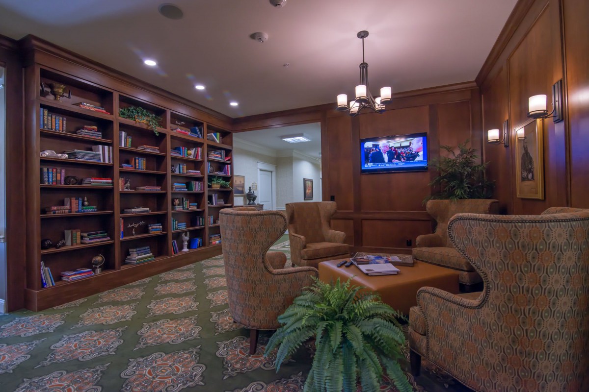 A cozy library with comfortable seating, bookshelves, and a television.