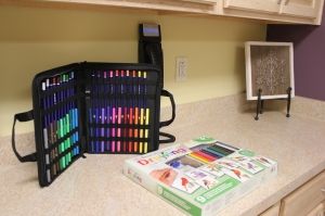 A collection of colorful markers and pens organized in a carrying case on a countertop.