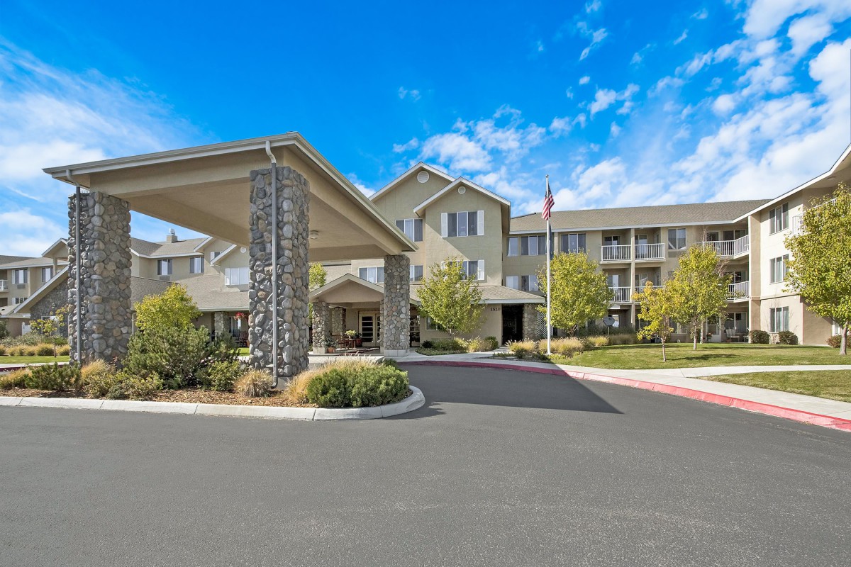A well-maintained building entrance with landscaped surroundings under a clear blue sky.