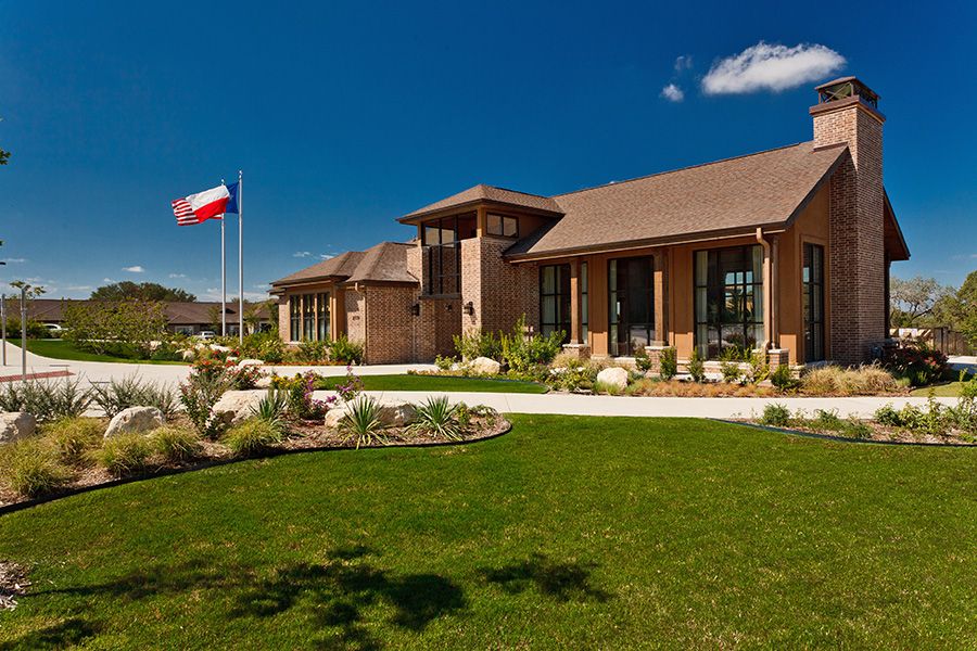 A modern building with a landscaped lawn and a flag under a clear blue sky.