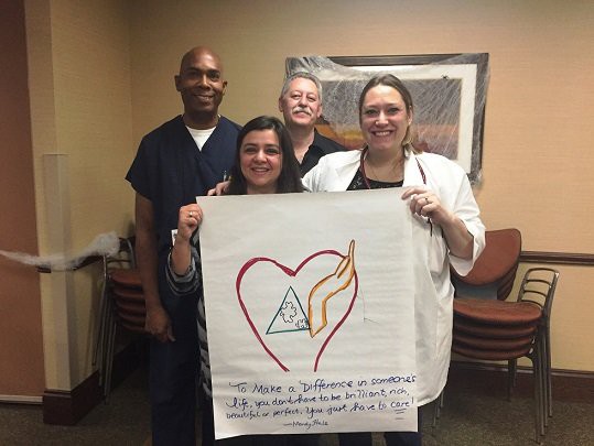 A group of healthcare professionals holding a poster with a heart design and text.