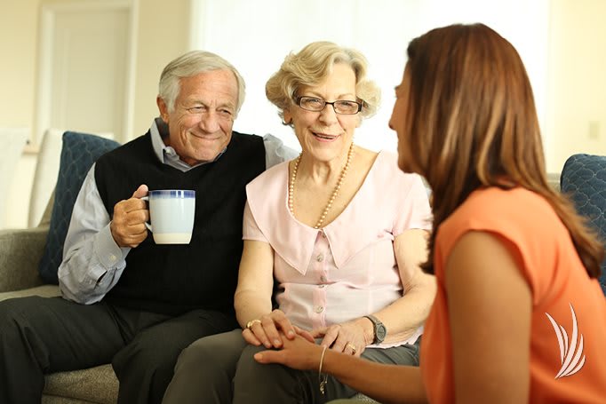 An elderly couple enjoying a conversation with a young woman indoors.
