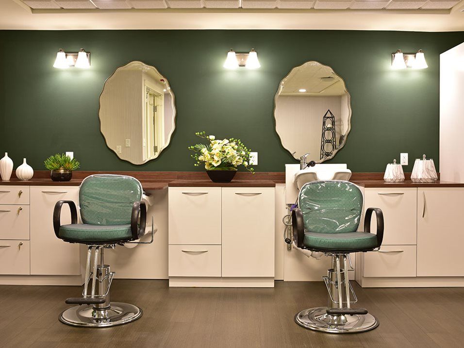 A stylish barbershop interior with two chairs, mirrors, and elegant lighting.