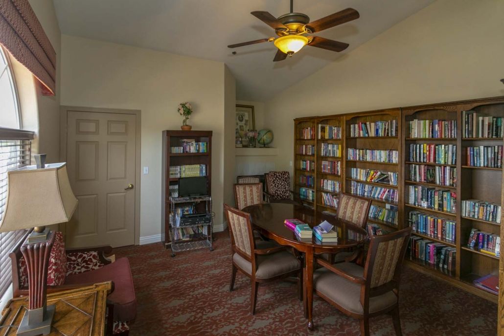 A cozy library room with bookshelves, a table, and chairs for reading.