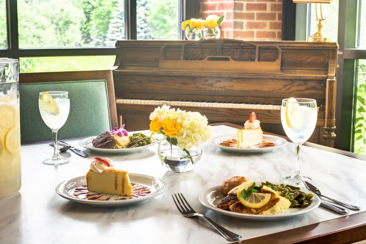 A beautifully set dining table with various dishes and desserts, accompanied by a bouquet of yellow flowers.