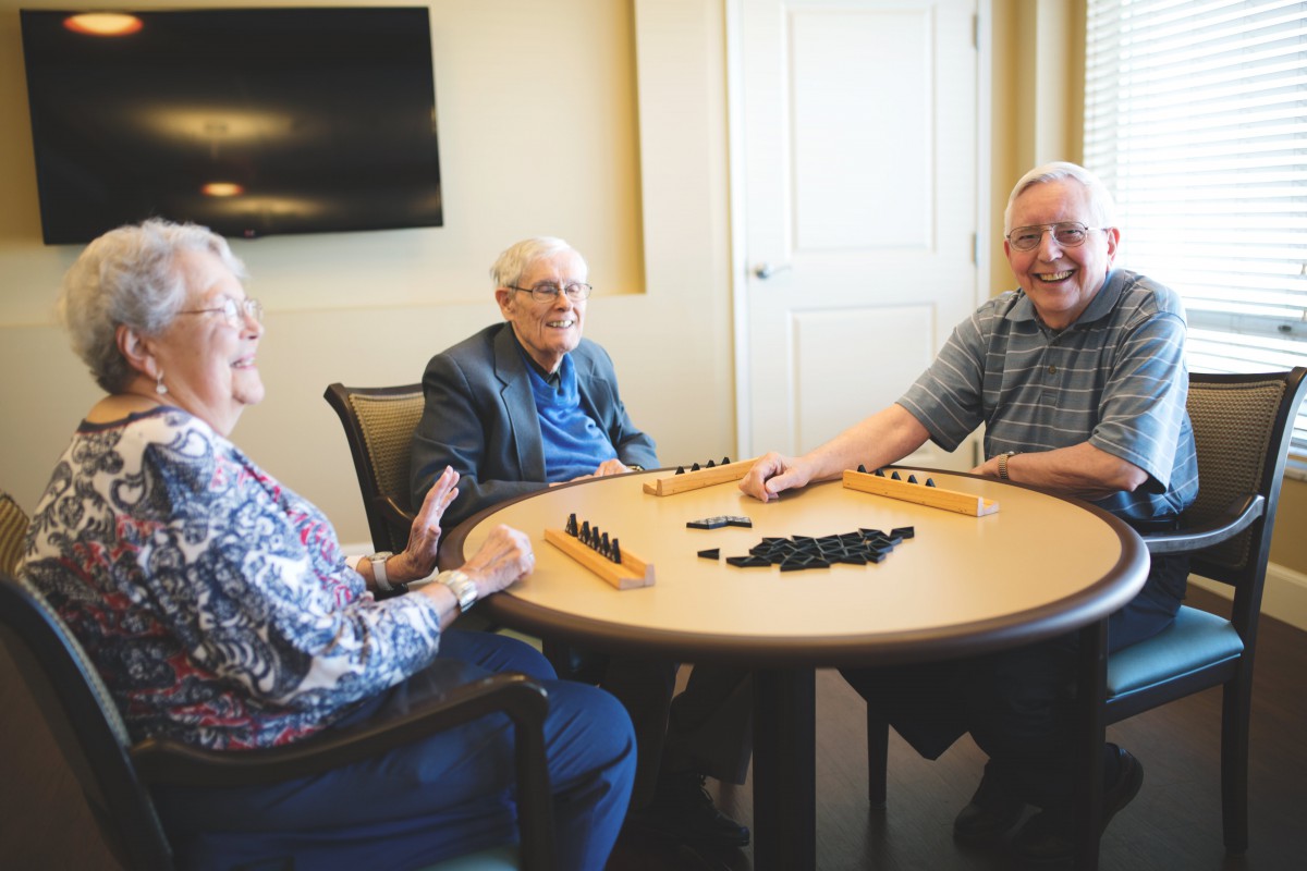 A group of seniors enjoying a game together at a round table indoors.