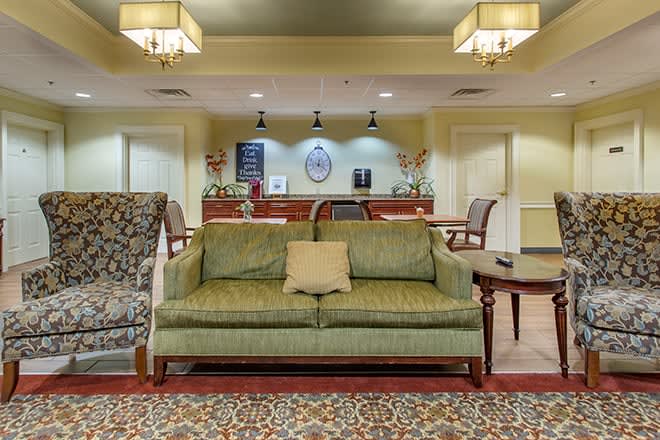 A cozy lobby area with a green sofa and a reception desk in the background.