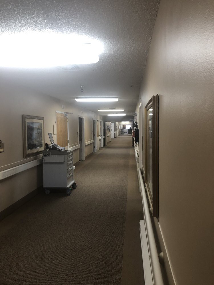 A quiet hospital hallway with equipment and framed art on the walls.