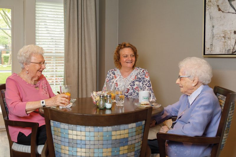 Three elderly women enjoying a conversation at a table.
