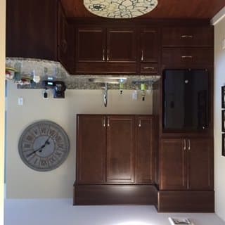A modern kitchen with dark wood cabinets and various appliances.