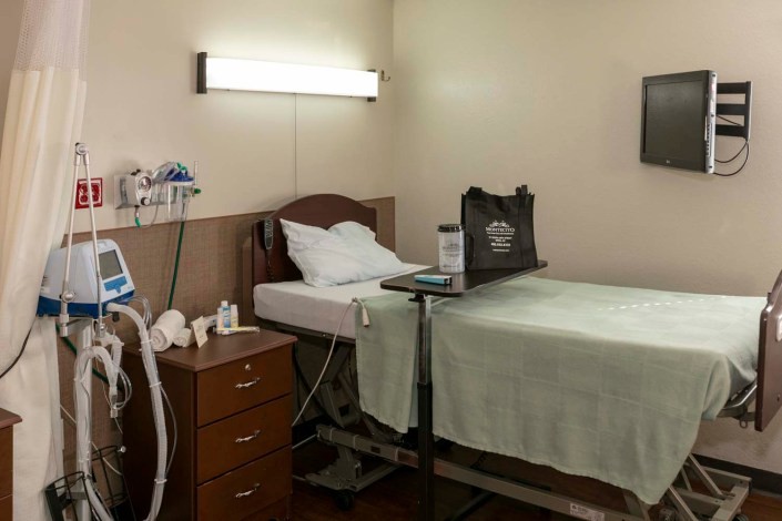 A clean and well-equipped hospital room with a bed and medical equipment.