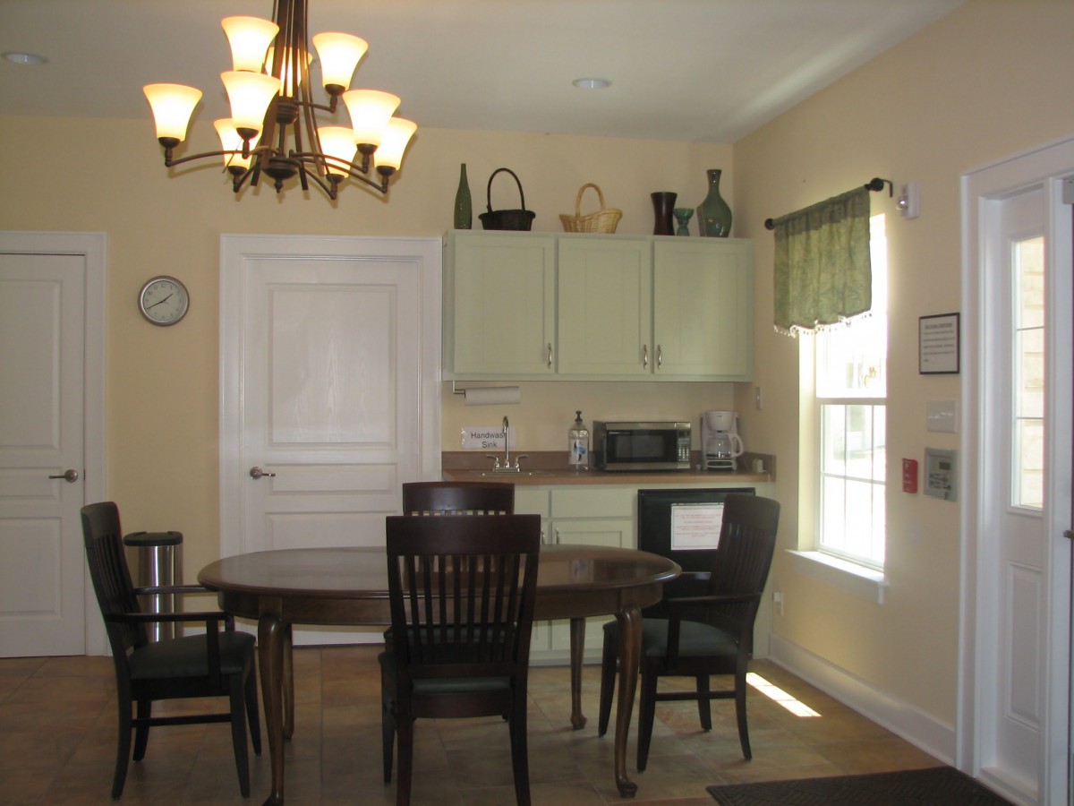 A cozy dining area with a wooden table, chairs, and cabinets under warm lighting.