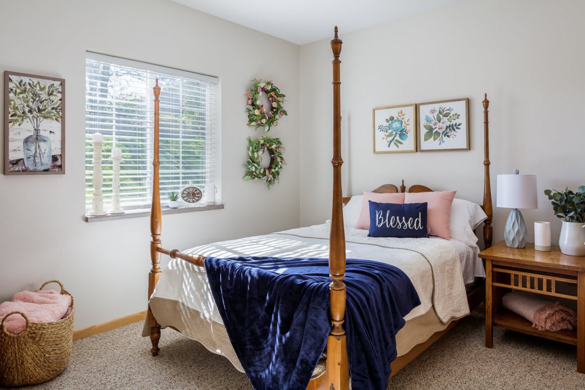 A cozy bedroom with a four-poster bed and decorative elements like wreaths and framed wall art.