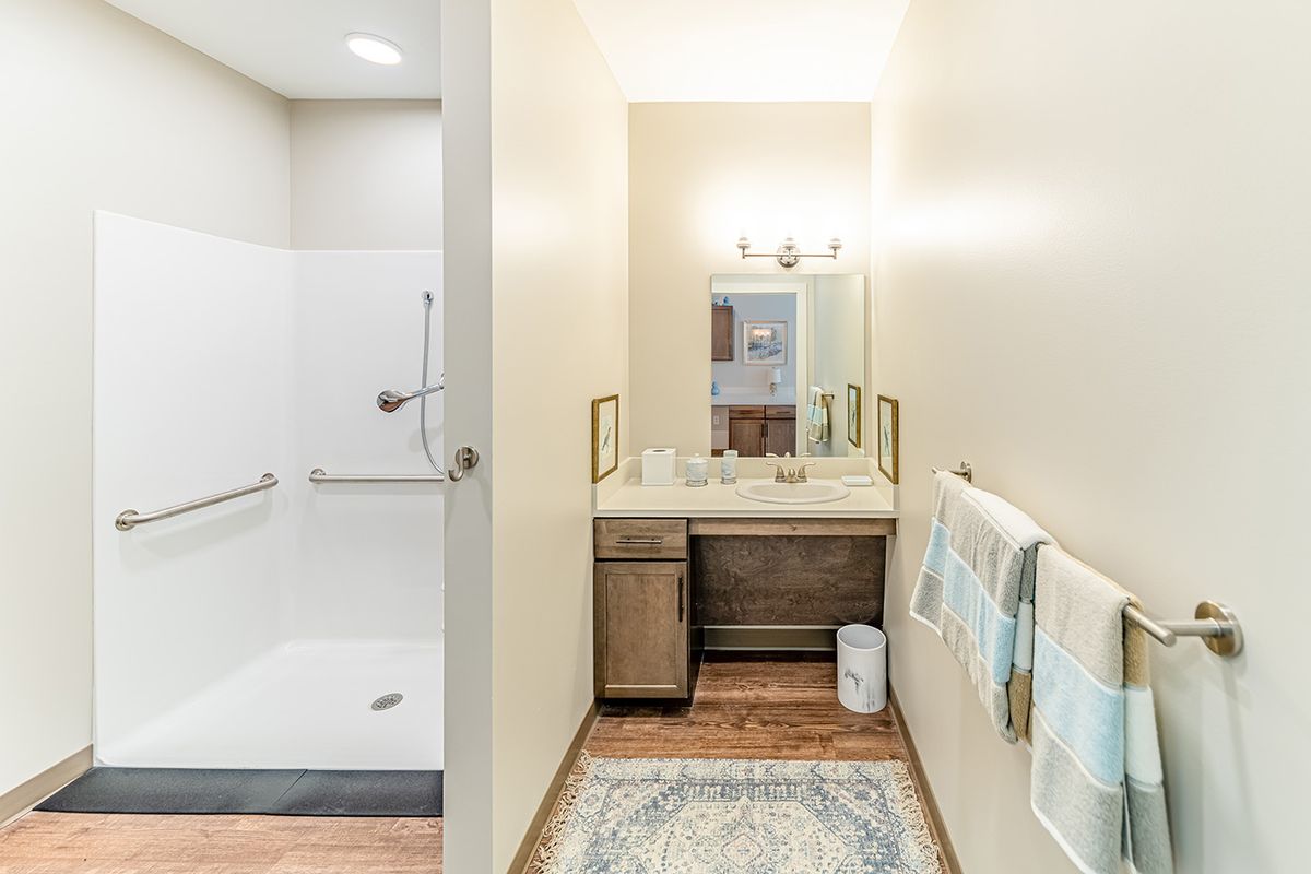 A modern bathroom with a vanity, mirror, and shower area.