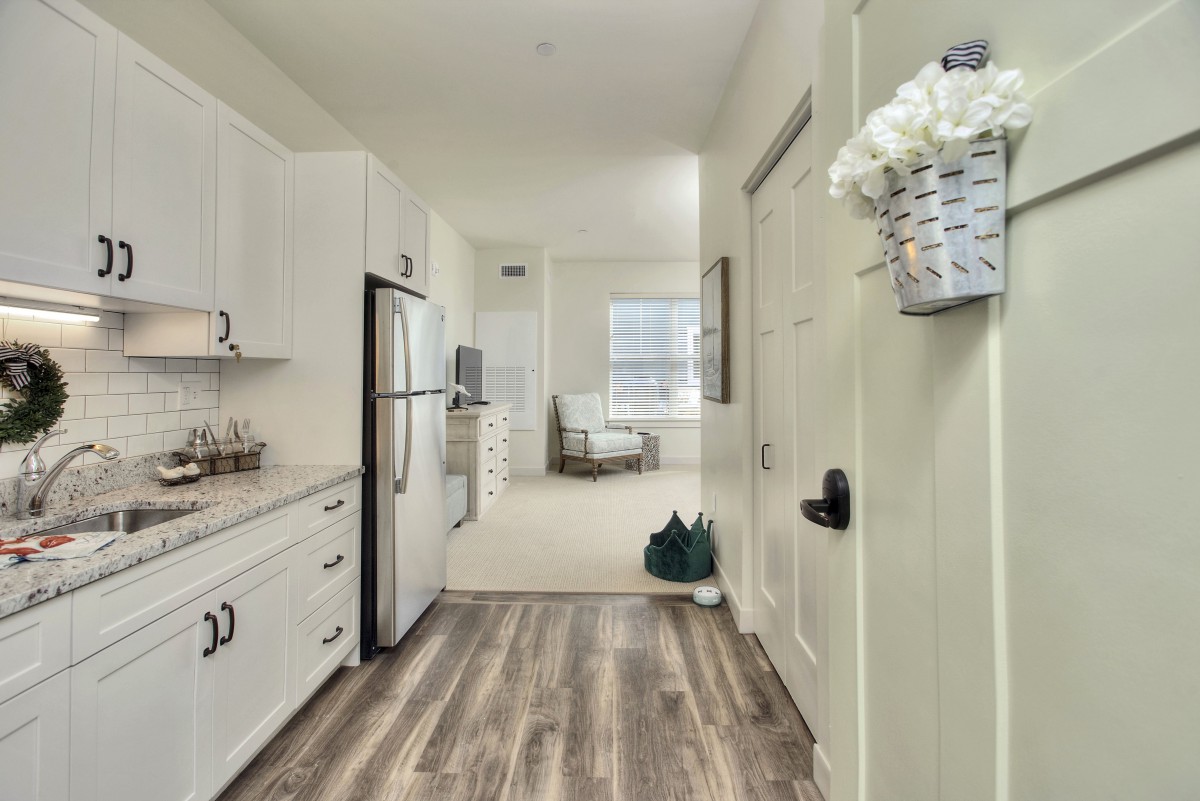 A modern kitchen interior with white cabinets and stainless steel appliances in a bright apartment.