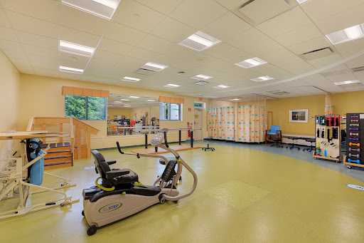 A bright and spacious exercise room equipped with gym machines and a large mirrored wall.